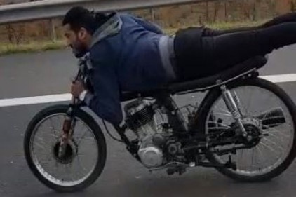 Motosikletin üzerinde boylu boyunca uzanarak yolculuk ettiler 