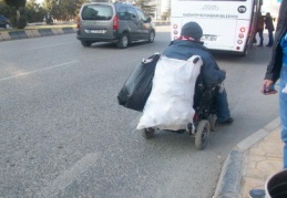 Tekerlekli sandalye ile kağıt topluyor
